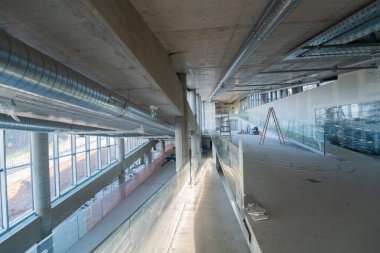 Yapım aşamasındaki modern bir iş binasının büyüleyici bir görüntüsü, çiğ endüstriyel iç mekânını, gün batımının sıcak, altın sarısı renkleri ile yıkanmış çelik kirişleri ve beton duvarlarıyla sergiliyor.. 