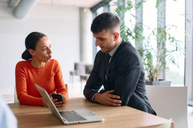 Genç, çeşitli bir iş ekibi modern bir ofiste birlikte oturuyor, fikir ve iş planlarını paylaşıyor, gelecekteki başarı için işbirliği ve yenilikleri teşvik ediyor.