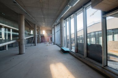 Yapım aşamasındaki modern bir iş binasının büyüleyici bir görüntüsü, çiğ endüstriyel iç mekânını, gün batımının sıcak, altın sarısı renkleri ile yıkanmış çelik kirişleri ve beton duvarlarıyla sergiliyor.. 