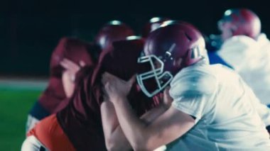 Profesyonel Amerikan futbol takımları çarpışıyor dramatik bir oyun başlıyor ve gol atmak için şiddetli bir mücadele veriyorlar. Sporcular, ağır çekimde yoğun bir şekilde mücadele ederek, saldırganca mücadele ediyorlar.
