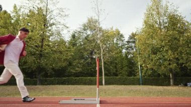 İş adamı atletizm pistinde koşarken engelden atlıyor. Yüksek kalite 4 bin yavaş çekim görüntüsü