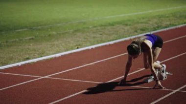 Atletizm atletizm sprint yarışı koşucusu koyu bir arka planda, stadyumun pistinde spor ayakkabılarla koşu koşusuna çıkıyor. Yavaş çekim