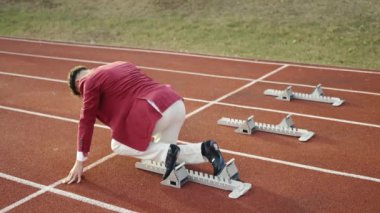 İş adamı yarış pistinde koşmaya hazırlanıyor. Ağır çekimde patlayıcı.