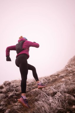 Bir dağda ultra-maraton koşusu için koşan bayan sporcu. Açık havada antrenman yapan koşucu bir kadın aktif ve zinde bir hayat sürüyor. Sabahın erken saatlerinde koşucular silueti.
