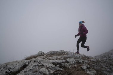 Bir dağda ultra-maraton koşusu için koşan bayan sporcu. Açık havada antrenman yapan koşucu bir kadın aktif ve zinde bir hayat sürüyor. Sabahın erken saatlerinde koşucular silueti.