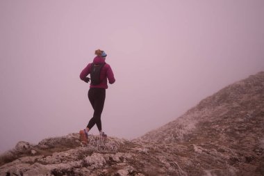 Bir dağda ultra-maraton koşusu için koşan bayan sporcu. Açık havada antrenman yapan koşucu bir kadın aktif ve zinde bir hayat sürüyor. Sabahın erken saatlerinde koşucular silueti.