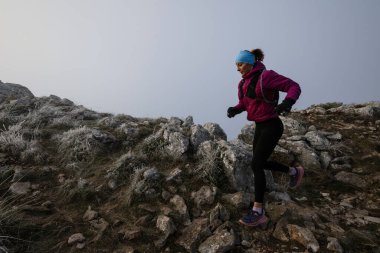 Bir dağda ultra-maraton koşusu için koşan bayan sporcu. Açık havada antrenman yapan koşucu bir kadın aktif ve zinde bir hayat sürüyor. Sabahın erken saatlerinde koşucular silueti.