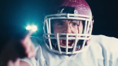 Profesyonel Amerikan futbolcusunun portresi miğferli, dramatik bir ışık altında maça hazır kusuyor. Takım oyunu ve ekstrem spor ruhu iş dünyası liderliği kavramı. Sinema yavaşlığı