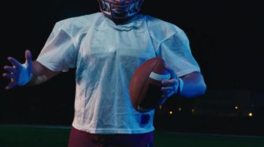 Profesyonel Amerikan futbolcusunun portresi miğferli, dramatik bir ışık altında maça hazır kusuyor. Takım oyunu ve ekstrem spor ruhu iş dünyası liderliği kavramı. Sinema yavaşlığı
