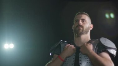 Bir Amerikan futbolcusunun yakın plan portresi yoğun bir antrenmandan sonra terliyor, atletizm ve kararlılık sergiliyor. Sporla ilgili içerik ve motivasyonel görseller için ideal