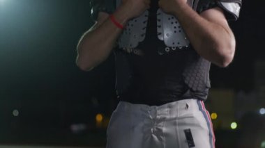 Bir Amerikan futbolcusunun yakın plan portresi yoğun bir antrenmandan sonra terliyor, atletizm ve kararlılık sergiliyor. Sporla ilgili içerik ve motivasyonel görseller için ideal