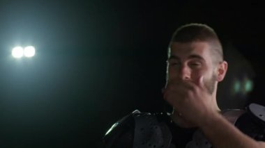 Bir Amerikan futbolcusunun yakın plan portresi yoğun bir antrenmandan sonra terliyor, atletizm ve kararlılık sergiliyor. Sporla ilgili içerik ve motivasyonel görseller için ideal