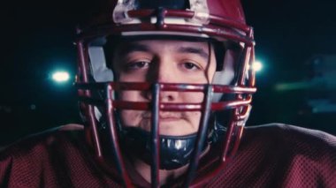 Profesyonel Amerikan futbolcusunun portresi miğferli, dramatik bir ışık altında maça hazır kusuyor. Takım oyunu ve ekstrem spor ruhu iş dünyası liderliği kavramı. Sinema yavaşlığı