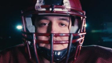 Profesyonel Amerikan futbolcusunun portresi miğferli, dramatik bir ışık altında maça hazır kusuyor. Takım oyunu ve ekstrem spor ruhu iş dünyası liderliği kavramı. Sinema yavaşlığı