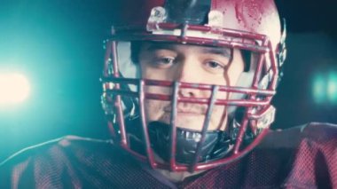 Profesyonel Amerikan futbolcusunun portresi miğferli, dramatik bir ışık altında maça hazır kusuyor. Takım oyunu ve ekstrem spor ruhu iş dünyası liderliği kavramı. Sinema yavaşlığı