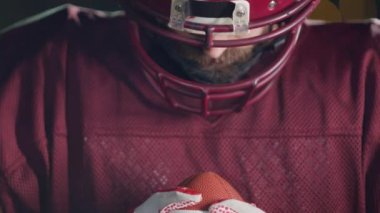 Profesyonel Amerikan futbolcusunun portresi miğferli, dramatik bir ışık altında maça hazır kusuyor. Takım oyunu ve ekstrem spor ruhu iş dünyası liderliği kavramı. Sinema yavaşlığı