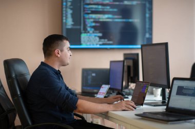 Bir programcı ofisinde otururken akıllı telefon uygulamalarını özenle test ediyor. Yüksek kalite fotoğraf