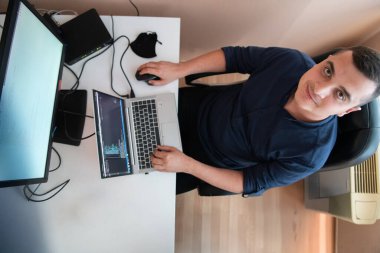 Akıllı telefon uygulamalarını ofisinde otururken özenle test eden programcının üst görünümü