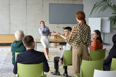 Çeşitli iş adamları modern bir ofiste dikkatle oturup, bir eğitmenin önderliğindeki bir eğitim oturumunda aktif olarak en son teknolojik gelişmelere odaklanırlar.