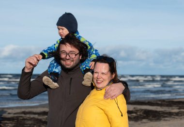 Mutlu bir aile, serin bir sonbahar plajı boyunca yürür. Genç oğulları sevinçle koşar, taze rüzgar ve dindirici dalgalar onları bir anda kucaklarken kalıcı anılar yaratır.