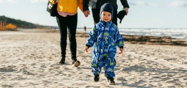 Mutlu bir aile, serin bir sonbahar plajı boyunca yürür. Genç oğulları sevinçle koşar, taze rüzgar ve dindirici dalgalar onları bir anda kucaklarken kalıcı anılar yaratır.