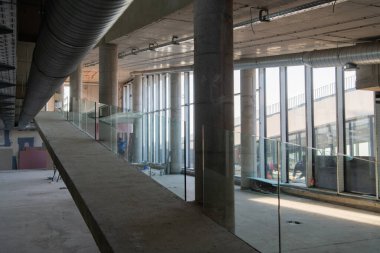 Yapım aşamasındaki modern bir iş binasının büyüleyici bir görüntüsü, çiğ endüstriyel iç mekânını, gün batımının sıcak, altın sarısı renkleri ile yıkanmış çelik kirişleri ve beton duvarlarıyla sergiliyor.. 