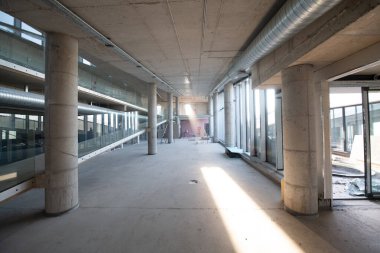 Yapım aşamasındaki modern bir iş binasının büyüleyici bir görüntüsü, çiğ endüstriyel iç mekânını, gün batımının sıcak, altın sarısı renkleri ile yıkanmış çelik kirişleri ve beton duvarlarıyla sergiliyor.. 