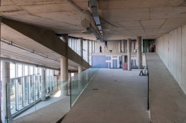 Yapım aşamasındaki modern bir iş binasının büyüleyici bir görüntüsü, çiğ endüstriyel iç mekânını, gün batımının sıcak, altın sarısı renkleri ile yıkanmış çelik kirişleri ve beton duvarlarıyla sergiliyor.. 