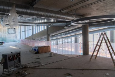 Yapım aşamasındaki modern bir iş binasının büyüleyici bir görüntüsü, çiğ endüstriyel iç mekânını, gün batımının sıcak, altın sarısı renkleri ile yıkanmış çelik kirişleri ve beton duvarlarıyla sergiliyor.. 