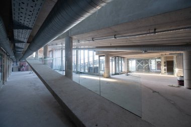 Yapım aşamasındaki modern bir iş binasının büyüleyici bir görüntüsü, çiğ endüstriyel iç mekânını, gün batımının sıcak, altın sarısı renkleri ile yıkanmış çelik kirişleri ve beton duvarlarıyla sergiliyor.. 