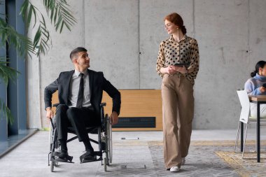 Director in a Wheelchair Engaging in a Business Discussion with a Colleague While Navigating a Modern Office. clipart