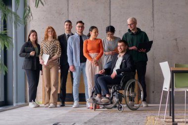 Çağdaş bir ofiste tekerlekli sandalyede müdürle işbirliği yapan çok ırklı iş adamları..