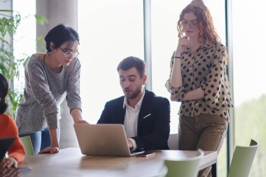 Çeşitli etnik çeşitlilikte bir iş ekibi, modern ofis ortamında strateji ve çözümleri tartışan bir işbirliği toplantısı düzenliyor..