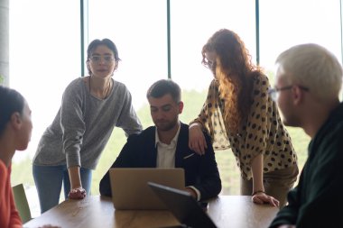 A diverse team of business professionals, along with the company director, reviewing business successes on a laptop in a modern office, discussing strategy and progress. clipart