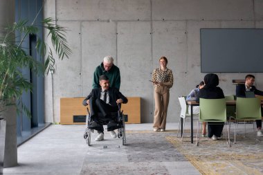 A diverse team of business colleagues, including a director in a wheelchair, engages in a collaborative discussion as they move together through a modern office space.  clipart