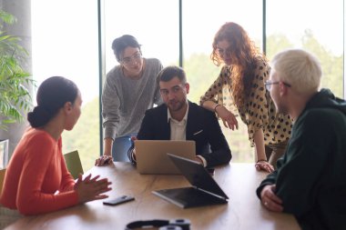 A diverse team of business professionals, along with the company director, reviewing business successes on a laptop in a modern office, discussing strategy and progress. clipart