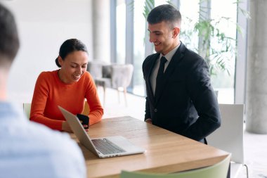 Genç, çeşitli bir iş ekibi modern bir ofiste birlikte oturuyor, fikir ve iş planlarını paylaşıyor, gelecekteki başarı için işbirliği ve yenilikleri teşvik ediyor.