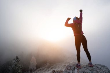 Kadın adam gün batımında bir dağın tepesinde duruyor. Hedefler ve başarılar konsept fotoğraf birleşimi. Kavramsal görüş, yürüyüş ya da patika koşucusu dağlara bakar ve güneşin doğuşunun tadını çıkarır..