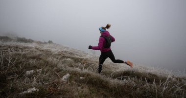 Bir dağda ultra-maraton koşusu için koşan bayan sporcu. Açık havada antrenman yapan koşucu bir kadın aktif ve zinde bir hayat sürüyor. Sabahın erken saatlerinde koşucular silueti.