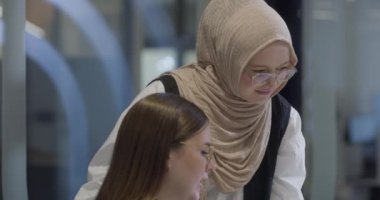 Bir tanesi tesettür takan çeşitli iş kadınlarından oluşan bir grup, bir dizüstü bilgisayara odaklanırken, tartışmalar ve problem çözme, göstermelik profesyonellik, takım çalışması ve etkili bir çalışma ile işbirliği yapıyor.