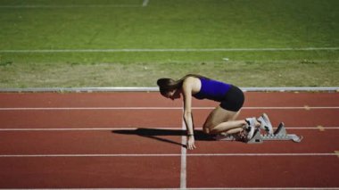 Atletizm atletizm sprint yarışı koşucusu koyu bir arka planda, stadyumun pistinde spor ayakkabılarla koşu koşusuna çıkıyor. Yavaş çekim