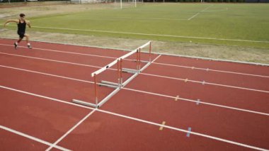 Stadyuma atletik zinde bir çift erkek ve kadın fırlatılıyor. Sıcak bir yaz öğleden sonrasında engellerin üzerinden atlamak. Yavaş Hareket İzleme Görüntüsü. 