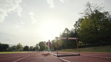 İş adamı atletizm pistinde koşarken engelden atlıyor. Yüksek kalite 4 bin yavaş çekim görüntüsü