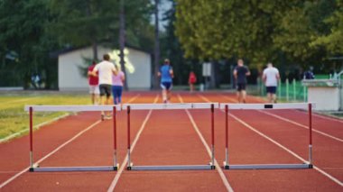 Stadyuma atletik zinde bir çift erkek ve kadın fırlatılıyor. Sıcak bir yaz öğleden sonrasında engellerin üzerinden atlamak. Yavaş Hareket İzleme Görüntüsü. 