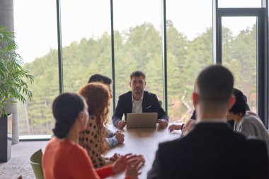 A diverse team of business professionals, along with the company director, reviewing business successes on a laptop in a modern office, discussing strategy and progress. clipart