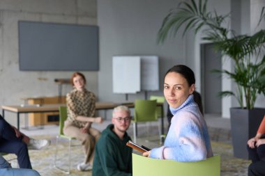 A diverse group of business professionals sits attentively in a modern office, actively participating in a training session led by an instructor, focusing on the latest technological advancements in clipart