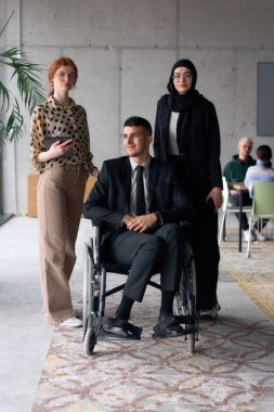 A diverse business team poses confidently, including a smiling director seated in a wheelchair, flanked by two professional female colleagues, one wearing a hijab and the other holding a tablet, in a clipart