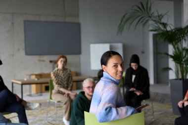 Çeşitli iş adamları modern bir ofiste dikkatle oturup, bir eğitmenin önderliğindeki bir eğitim oturumunda aktif olarak en son teknolojik gelişmelere odaklanırlar.