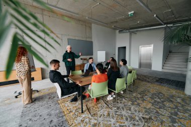 Çeşitli etnik çeşitlilikte bir iş ekibi, modern ofis ortamında strateji ve çözümleri tartışan bir işbirliği toplantısı düzenliyor..