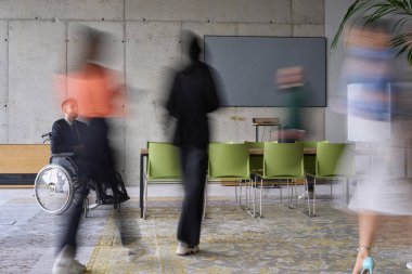 Bir konferans masasının etrafında acil olarak çalışan çeşitli bir iş ekibi, yöneticileri tekerlekli sandalyede oturmuş, görüşlerini beklerken bir toplantıda işbirliği yapıyor.. 